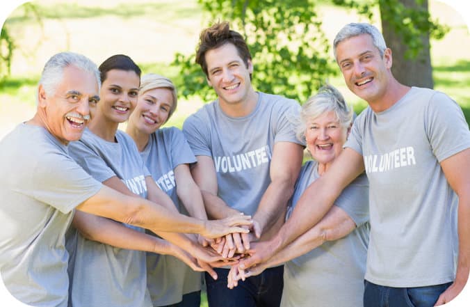 group of volunteers stacking their hands and smiling