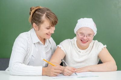 teacher helps young girl with Down Syndrome