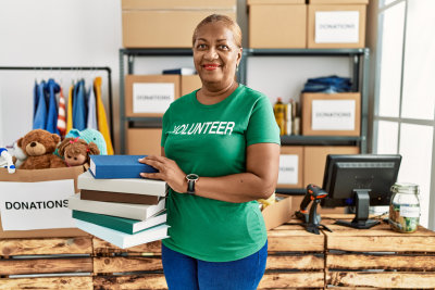 woman wearing volunteer uniform holding books at charity center