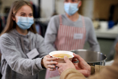 A volunteer giving a bowl of soup