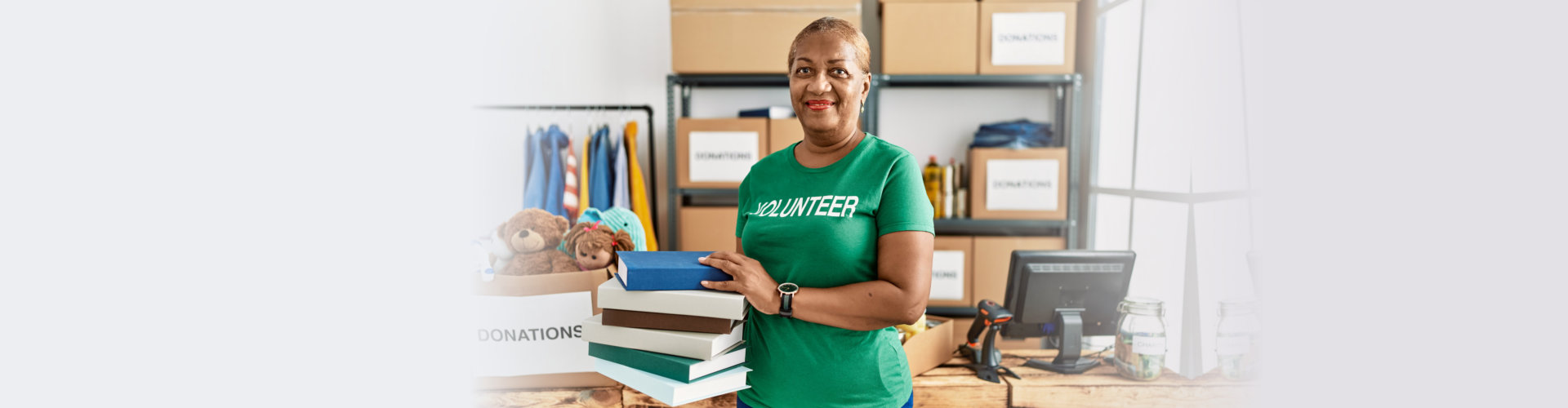 woman wearing volunteer uniform holding books at charity center